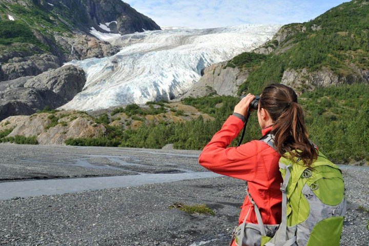 a young girl standing in front of a mountain