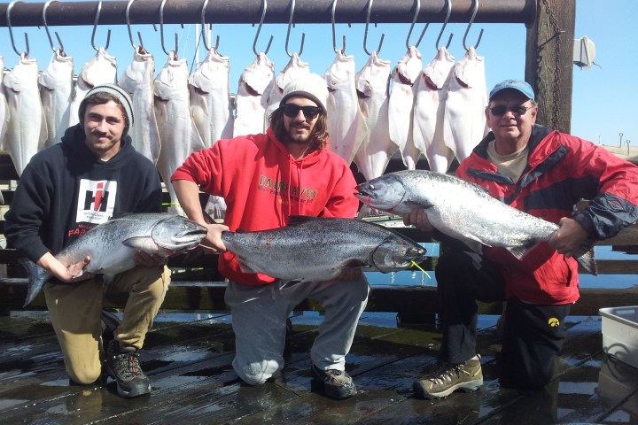 a group of people standing next to a man holding a fish
