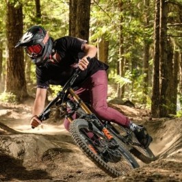 a man riding a bike down a dirt road in a forest