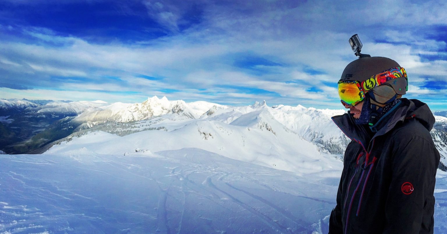 heli-snowboarding_t20_d10p2b-1536×804 a man standing on top of a snow covered mountain