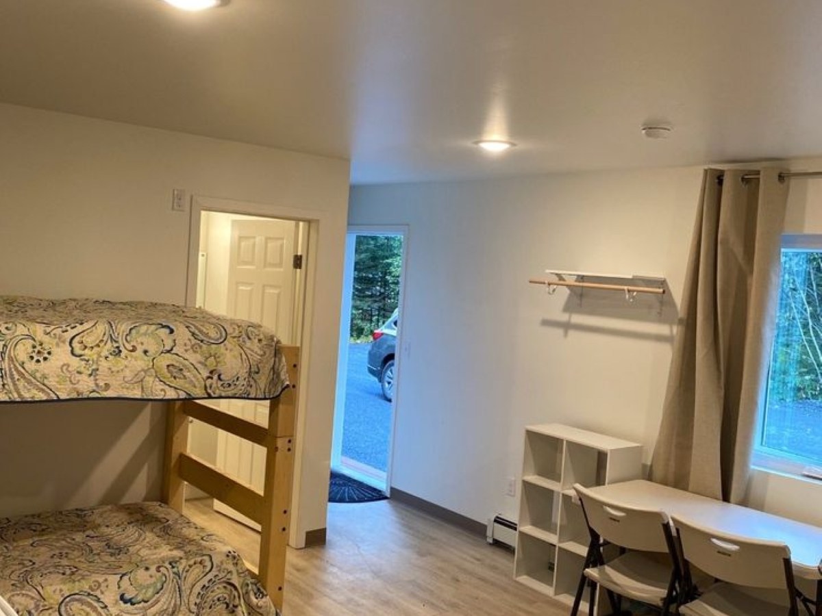 Room with bunk beds, small table, and open door to outside.