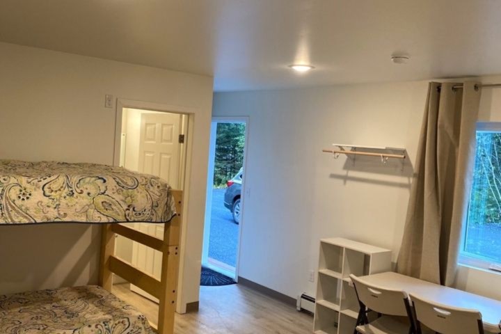 Room with bunk beds, small table, and open door to outside.