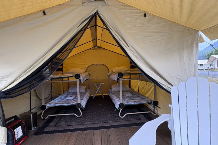 Tent with two bunk beds inside and a white chair outside on wooden decking.