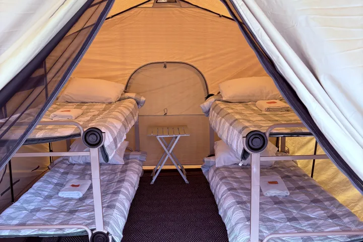 Interior of a tent with two bunk beds and a small table inside.