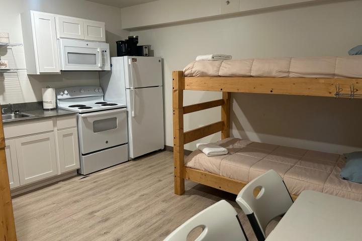 Compact kitchen with bunk beds and a table in a small, tidy room.