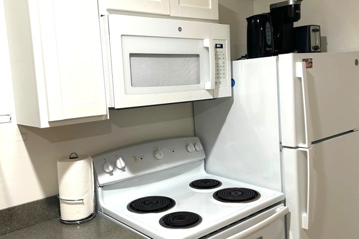 Compact kitchen with white appliances and cabinets.