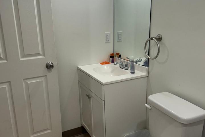 Small bathroom with a toilet, sink, mirror, and door.