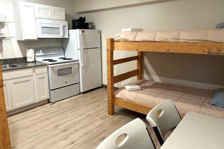 Small kitchenette with bunk beds and dining table in compact room.