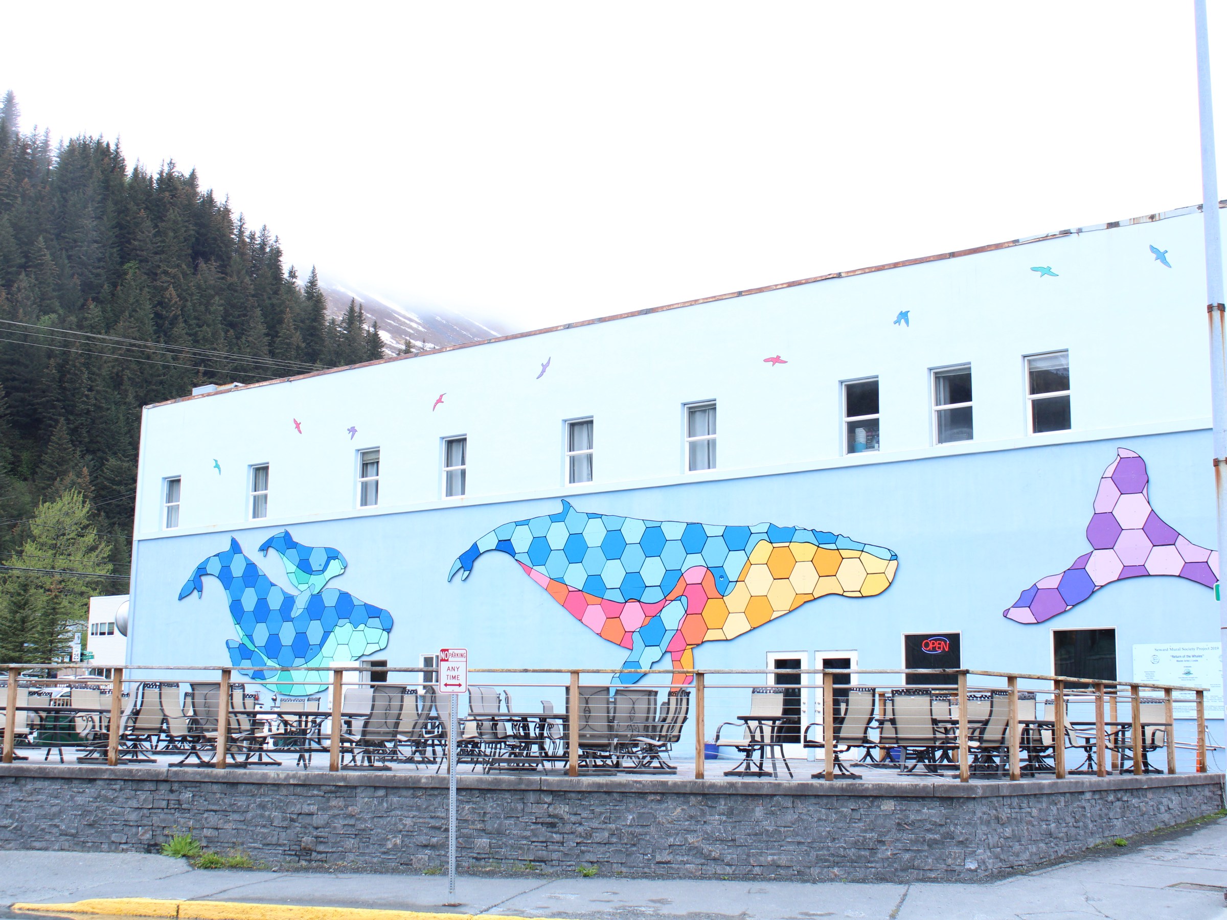 Building with colorful whale murals and outdoor seating on a sunny day.