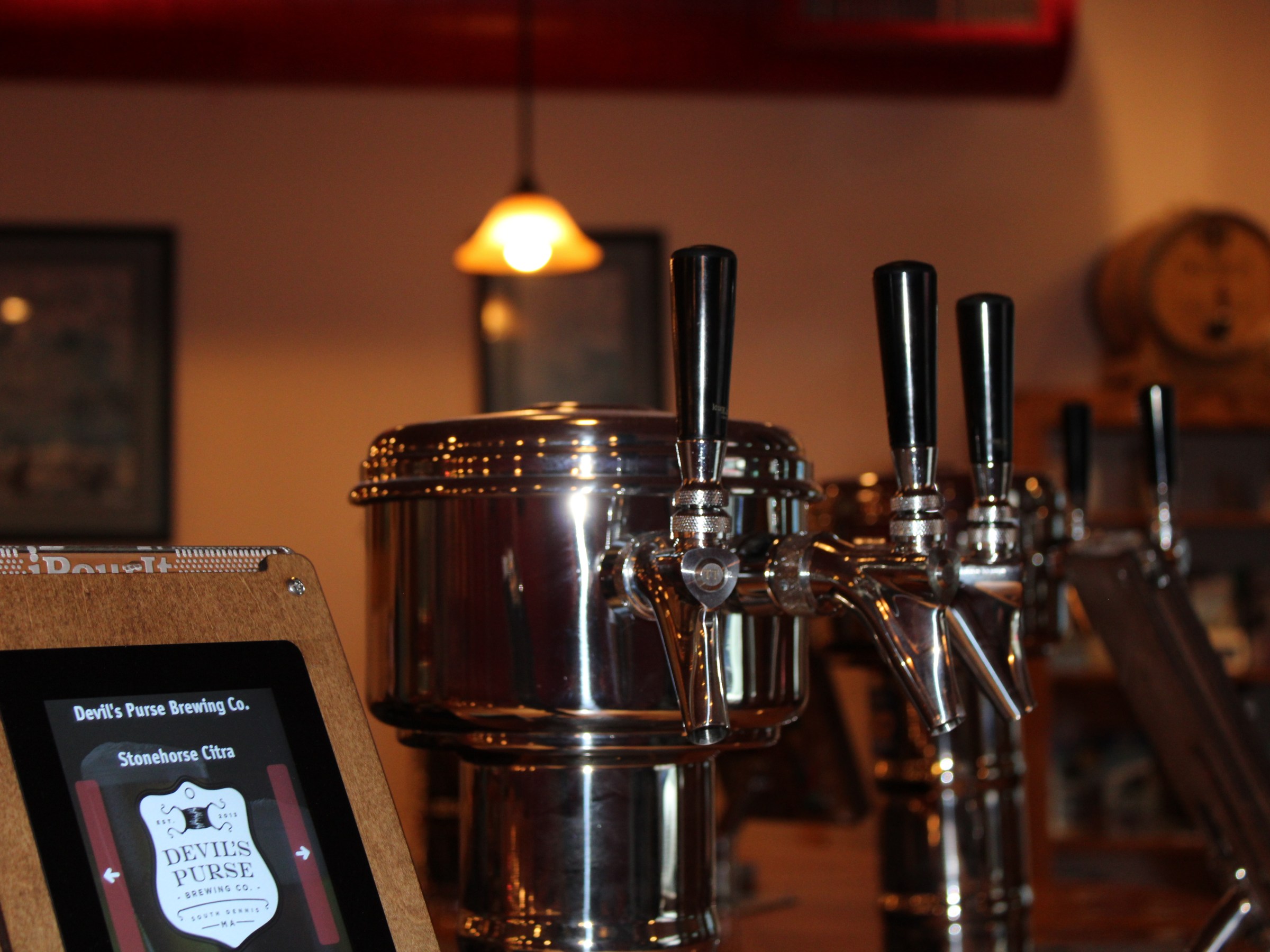 Bar taps and a digital menu with brewery details, dimly lit atmosphere.