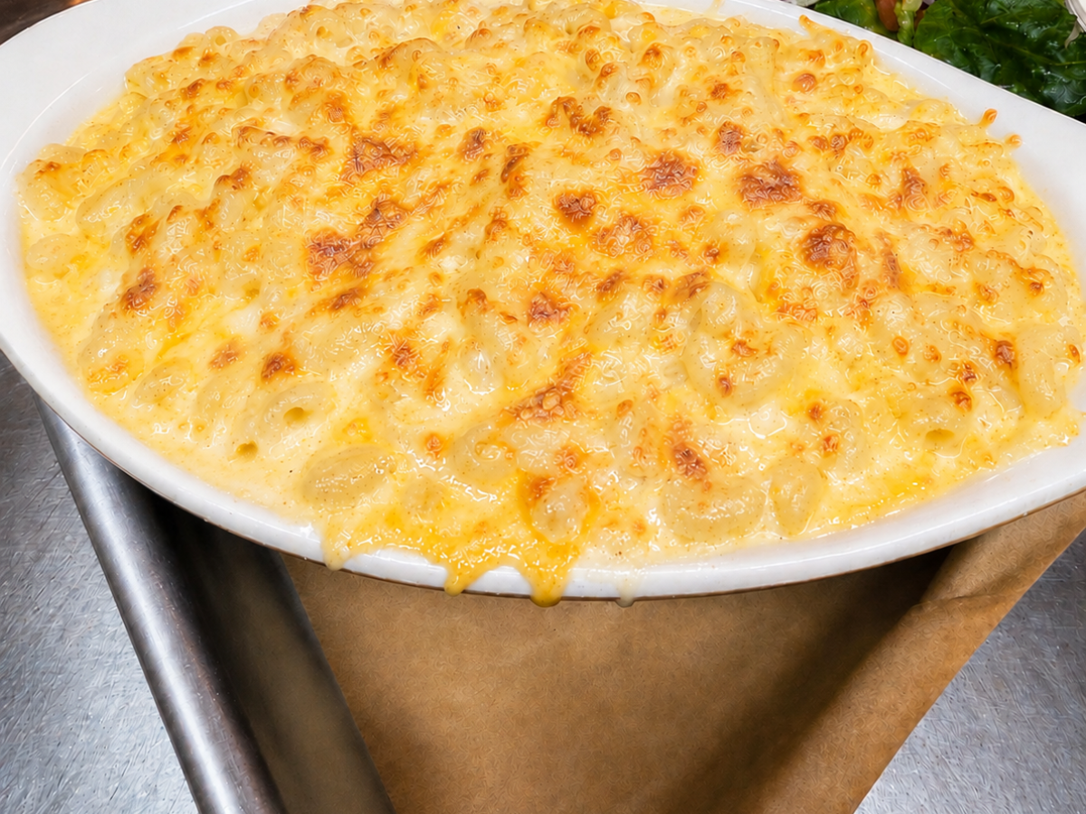 Baked mac and cheese in a white dish with a side salad.