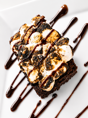 Chocolate brownie topped with toasted marshmallows and chocolate drizzle.